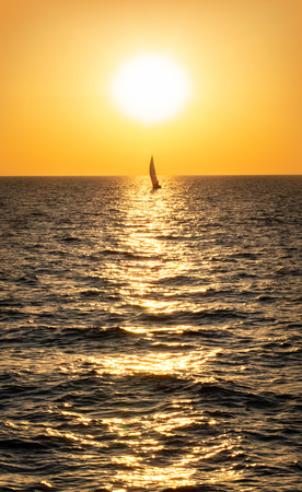 Yacht sailing along the horizon above the sea.の写真素材