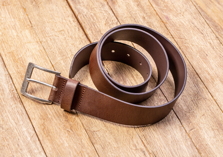 Stylish leather belt on wooden background