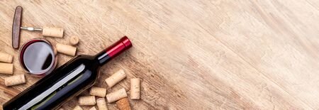Red wine bottle on wooden table with glass and corks and copy spaseの写真素材