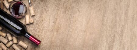Red wine bottle, glass and  corks on wooden table background with copy spaceの写真素材