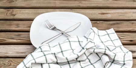 Round Plate with utensils and dish towel on light  wooden table background