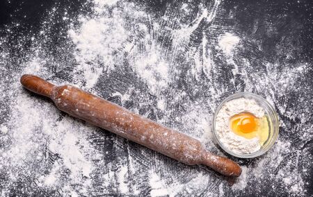 Baking background with the rolling pin with flour. On the dark table. Free space for text . Top view