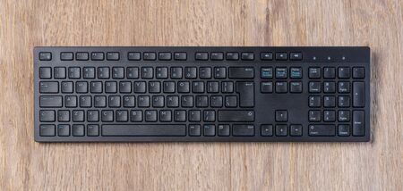 Top view of Full size wireless desktop computer keyboard on wooden table, with clipping path
