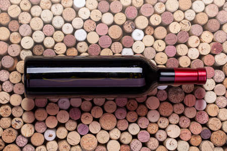red wine bottle on wine corks background top viewの写真素材