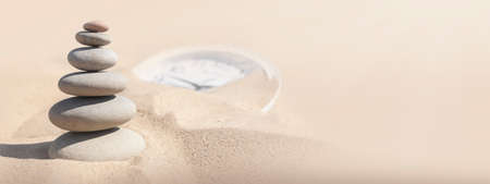 A stack of pebbles on the sand surface. The concept of zen, spa, relaxation. With space for textの写真素材