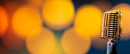 Retro microphone on golden bokeh color background with copy spaceの写真素材