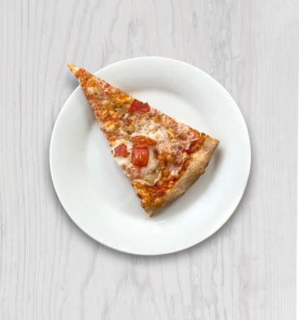 A slice of hot pizza with mozzarella cheese, ham, tomatoes on a plate, wood background, top view