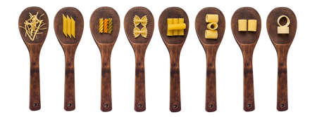 Wooden cooking spoons filled with various types of dry pasta isolated on a white backgroundの写真素材