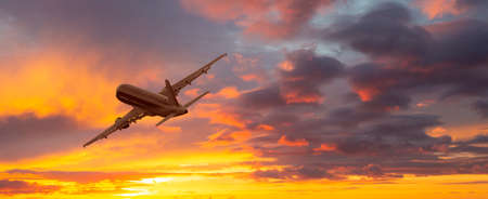 Airplane. Landscape with big passenger airplane is flying in the dramatic sky at colorful sunset....