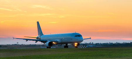 Passenger plane taxis onto the runway against the background of sunset