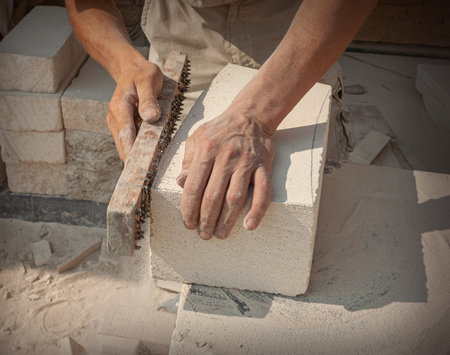 The sculptor's hands, which process a block of white stone on the desktop with tools. Hand Detailの写真素材