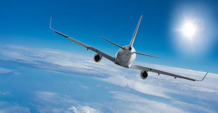 Passenger airplane flying at flight level high in the sky above the clouds and blue sky