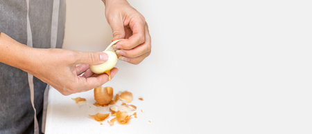 A woman's hands peeling an onion in a kitchen with copy spaceの写真素材