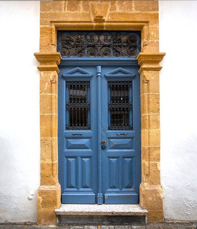 Traditional blue wooden door featuring intricate wrought iron grilles and a decorative transom...