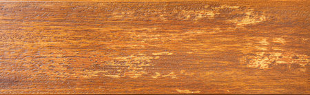 Wooden plank with distressed orange paint showing wood grain, creating a rustic textured backgroundの写真素材