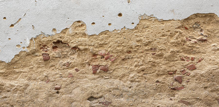 Weathered plaster wall revealing the underlying brickwork, showing a textured and aged surfaceの写真素材