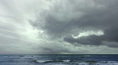 Dramatic cloudscape forming over a rough sea, creating a moody and captivating atmosphere