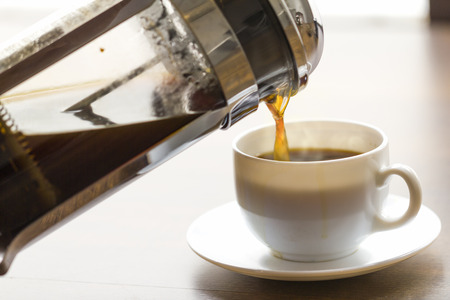 Coffee brewing in a French press in warm morning light;の写真素材
