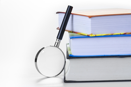 Colorful textbooks and magnifying glass isolated on white with left copy-space.の写真素材