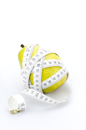 Diet problem, a pear and measuring tape isolated on whiteの写真素材