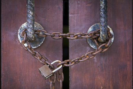 Brown old gate locked by old rusty chain and padlock の写真素材
