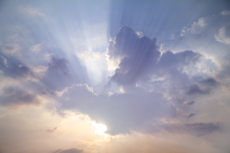 Sun shines through white clouds caused rays of light on hazy day blue sky