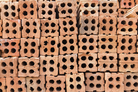 Stacks of hard orange-brown bricks block, a building construction material.