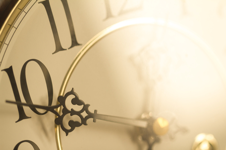 Face of classical grandfather pendulum clock closeup in golden light in concept of golden hour.