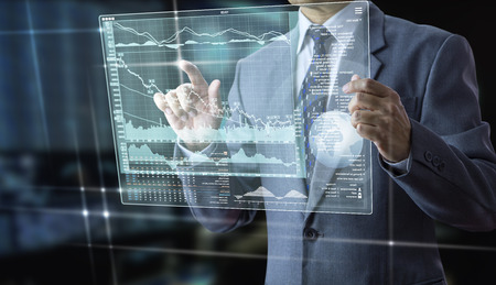 Businessman holding a futuristic modern tablet touch screen analysing on investment risk managment and return on investment analysisの写真素材