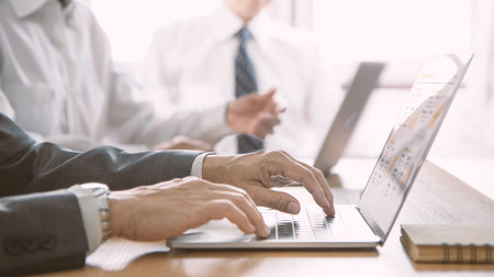 Three businessmen with laptop computer reviewing financial statements for a business performance,...