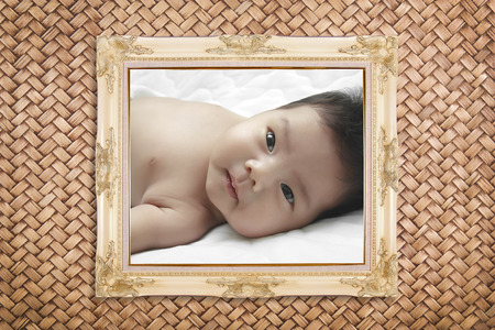 baby in white picture frame on rattan wall backgroundの写真素材
