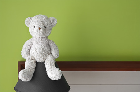 teddy bear sit on the lamp at headboard and green wall background for gift and surpriseの写真素材