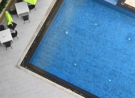 empty swimming pool with white table and chair set for exercise or relax on top view in the hotel