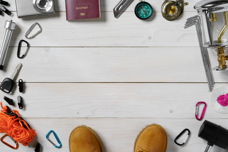 travel pattern frame for holiday passport, boots, lantern, wick, knife, camera, tripod, compass, clock, hammer, car key, carabiner, anchor and tent rope on white vintage wood floor or table top viewの写真素材