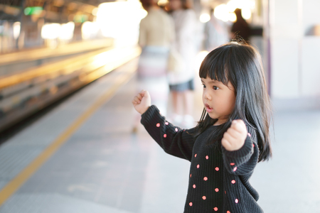 Asian children cute or kid girl waiting sky train or electric train on railway station and nature sunlight in the city for travel or transport with spaceの写真素材