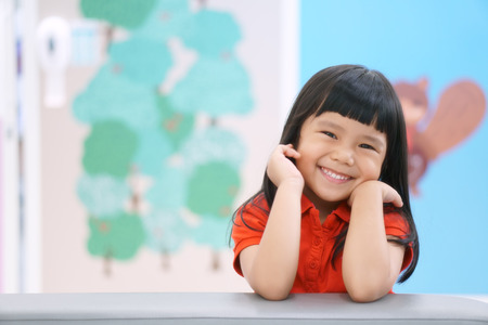Asian children cute or kid girl happy fun and smile with wear red shirt on sofa at preschool or nursery and child hospital with spaceの写真素材