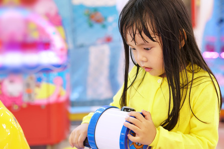 Asian children cute or kid girl naughty and fun with playing toy and game until sweating for activity and learning at nursery or playground with wear yellow shirtの写真素材