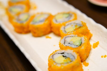 delicious sushi roll with shrimp eggs and seaweed on white dish and wood table for lunch or dinner at japanese food restaurant with spaceの写真素材