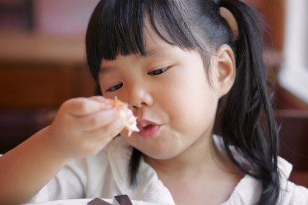 Asian children cute or kid girl eating shrimp or shrimp fried rice delicious food on table and white dish for lunch in the restaurantの写真素材