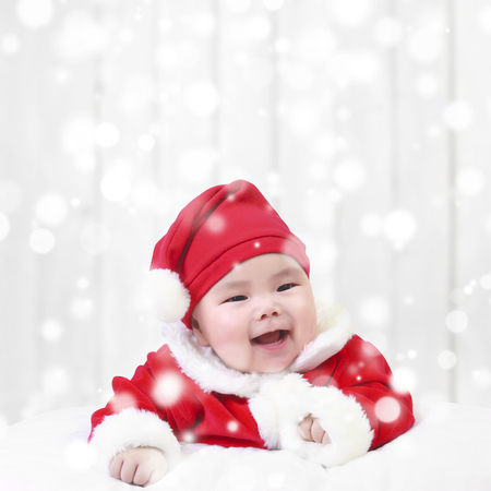 asian children cute or kid and baby wearing santa claus suit with fun or happy and smile in the winter and snow bokeh on white wood wall background for christmas or xmas and happy new year with spaceの写真素材