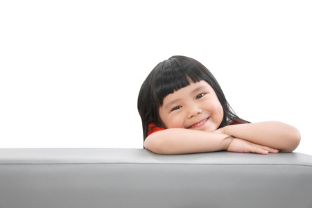 Asian children cute or kid girl happy fun and smile with wear red shirt on sofa at preschool or nursery and child hospital on white isolated with spaceの写真素材