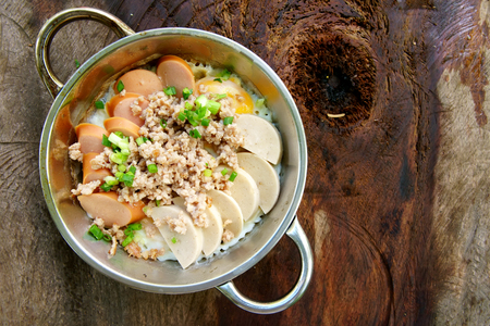 pan fried egg or panned egg food with sausage and pork chops in metal dish or plate on old wood table and top view for delicious or yummy breakfast in the morning with spaceの写真素材