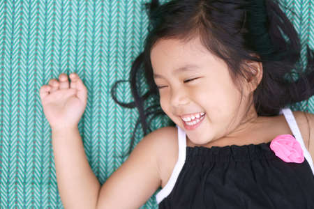 Asian child cute or kid girl close eye sleeping for relax on green mat and smile white teeth with...