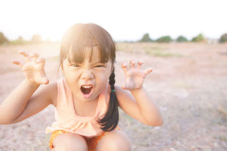 Asian child or kid girl smile and play funny or happy fun with make face threatening roar at...