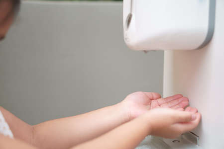 child or kid wash hands by hand wash gel machine or sanitizer for clean and healthy with kill bacteria or antibacterial at department store or school and restaurantの写真素材