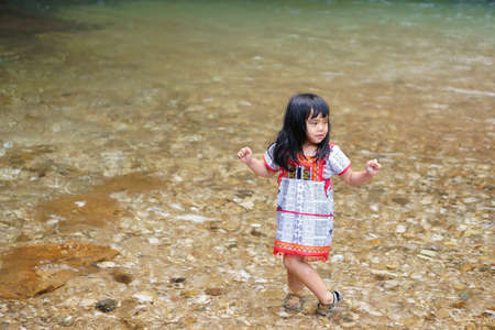 Asian child cute or kid girl hill tribe and smiling fun with enjoy happy for playing clear water...