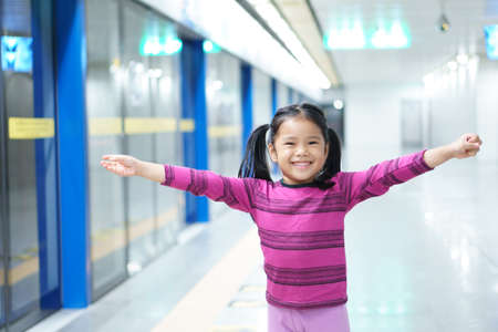 Asian child cute or kid girl waiting sky train or electric train with underground railways or metro...