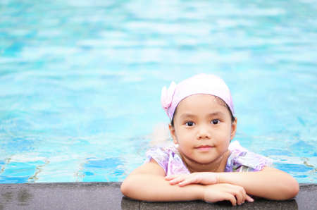 Asian child cute or kid girl wear swimming suit and cap on school swimming pool and smiling with...