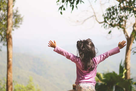 child cute or kid girl sightseeing and happy with hand up on nature holiday relax and vacation family travel for fresh in the morning at tree mountain with faint fog in Thong Pha Phum National Parkの写真素材