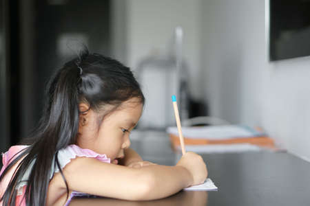 asian child cute or kid girl smile diligent writing or drawing and enjoy doing homework or happy...